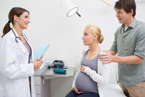 Smiling female doctor holding files while talking to a pregnant
